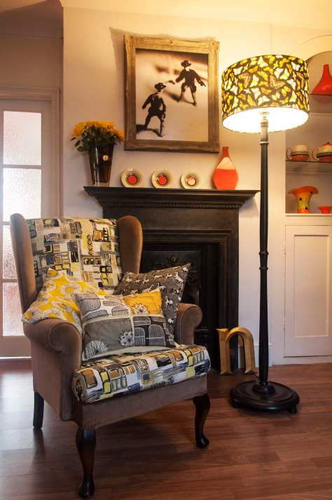 I recovered this old wing-back chair I found online in some gorgeous 1950s barkcloth and some donkey-brown velvet. I’ve teamed this with a couple of contemporary print cushions and a cushion I made myself with Lucienne Day-style prints. This colour scheme is predominantly grey, black, and yellow, but I’ve lifted it with the lampshade, which has orange, green and blues in the pattern, and with the orange accent ceramic pieces.